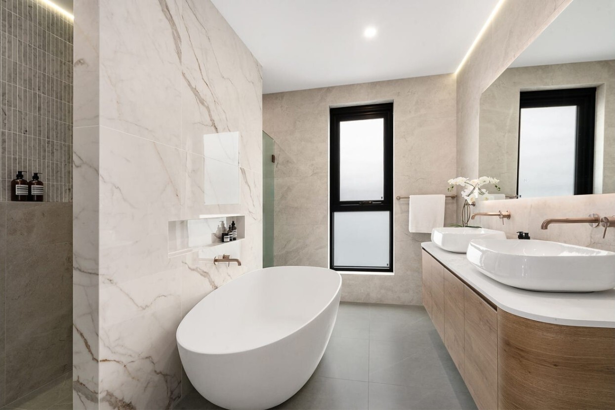 Zen-inspired Australian bathroom with large-format marble-look tiles, wooden cabinetry, & soft lighting